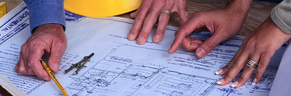 Hands working on a table with a blueprint.